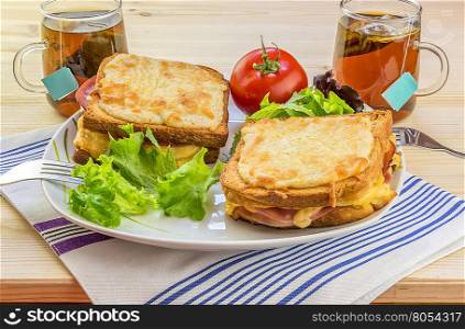 Cheese sandwiches and tee for two people - Tasty breakfast for two persons with specific french food, croque madame (with egg) and croque monsieur, seasoned with fresh salad and tea.