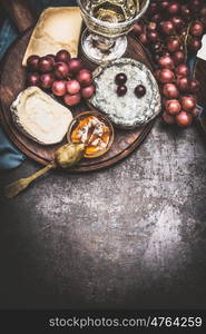 Cheese selection on rustic plate with wine, grape and Honey mustard sauce , dark vintage background, top view, border