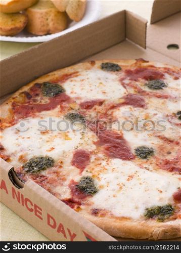 Cheese, Tomato And Pesto Pizza In A Take Away Box With Garlic Bread