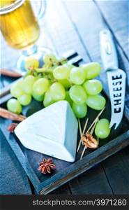 cheese with grape on a board and on a table