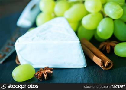 cheese with grape on a board and on a table