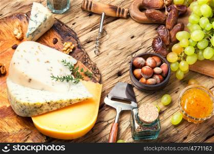cheese with nuts. Cheese with coriander and nettle and grapes on retro wooden background