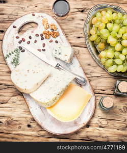 cheese with nuts. Cheese with coriander and nettle and grapes on retro wooden background