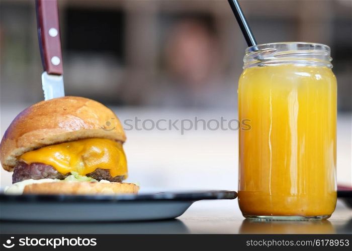 Cheeseburger and lemonade in jar on table