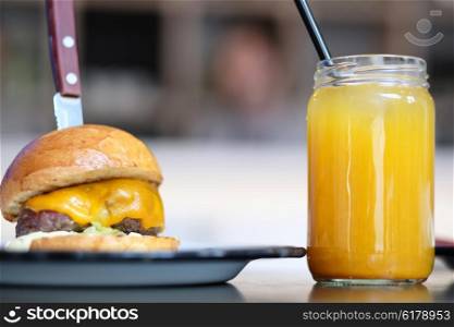 Cheeseburger and lemonade in jar on table