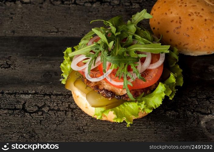 cheeseburger on an old wooden surface of dark color. hamburger with meat and tomato on an old wooden surface of dark color. cheeseburger on a wooden surface