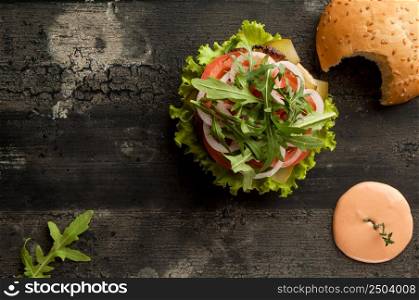 cheeseburger on an old wooden surface of dark color. hamburger with sauce and ketchup on an old wooden surface of dark color. cheeseburger on a wooden surface