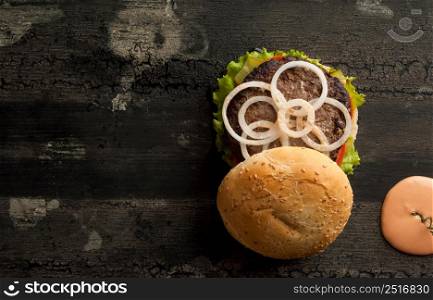 cheeseburger on an old wooden surface of dark color. hamburger with sauce and ketchup on an old wooden surface of dark color. cheeseburger on a wooden surface