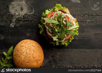 cheeseburger on an old wooden surface of dark color. hamburger with meat and tomato on an old wooden surface of dark color. cheeseburger on a wooden surface