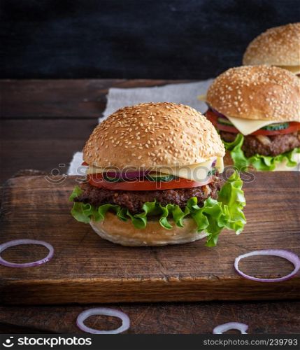 cheeseburger with meat patties and white sesame bun on a brown wooden table
