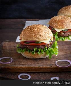 cheeseburger with meat patties and white sesame bun on a brown wooden table