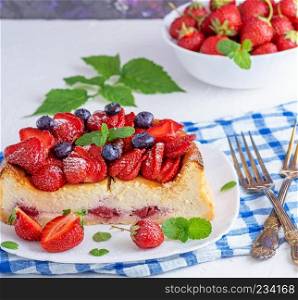 cheesecake made of cottage cheese and fresh strawberries on a white ceramic plate, close up