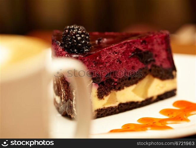 Cheesecake with blackberry on a plate and a cup of coffee, shallow dof.
