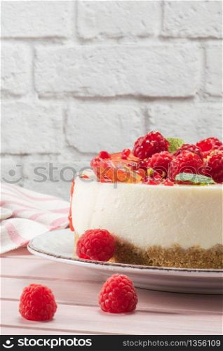 Cheesecake with fresh raspberries, plums and mint leaves.