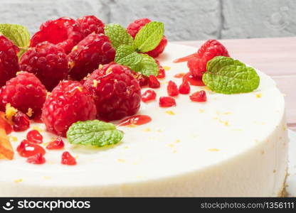 Cheesecake with fresh raspberries, plums and mint leaves.