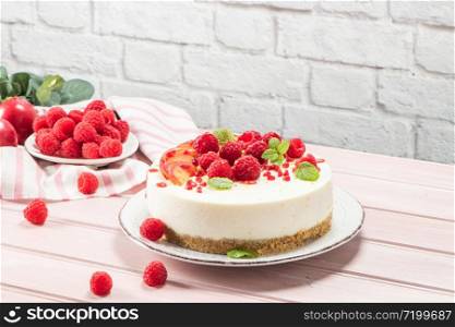 Cheesecake with fresh raspberries, plums and mint leaves.