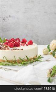 Cheesecake with raspberriees, chocolate, hazelnuts and rosemary leaves on kitchen coutertop