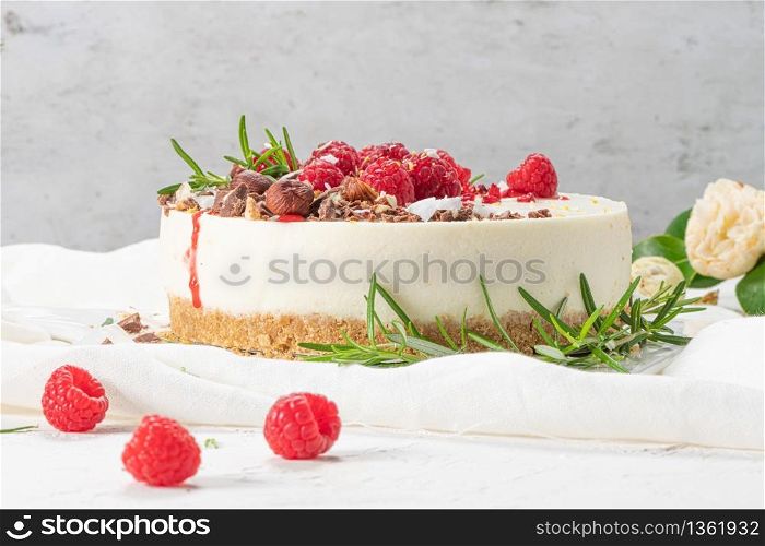 Cheesecake with raspberriees, chocolate, hazelnuts and rosemary leaves on kitchen coutertop