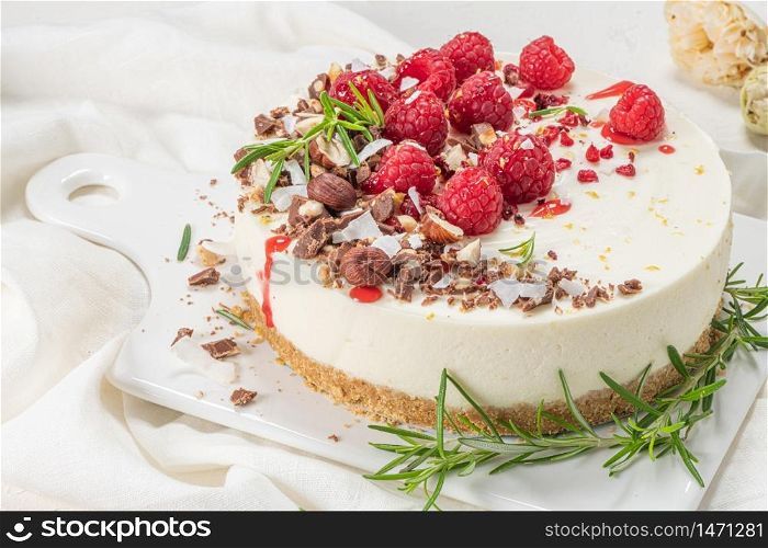 Cheesecake with raspberries, chocolate, hazelnuts and rosemary leaves on kitchen coutertop
