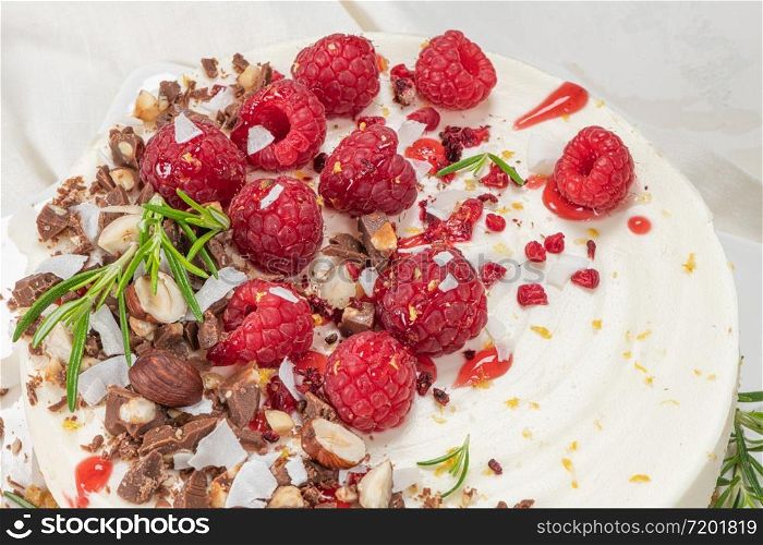 Cheesecake with raspberries, chocolate, hazelnuts and rosemary leaves on kitchen coutertop