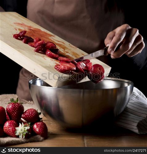 chef adding chopped strawberries bowl