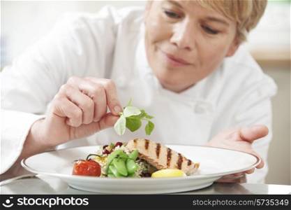 Chef Adding Garnish To Meal In Restaurant Kitchen