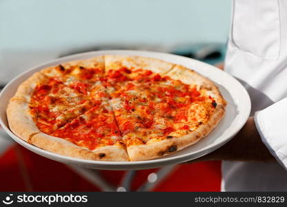 Chef and a plate of pizza in his hands. Selective focus.