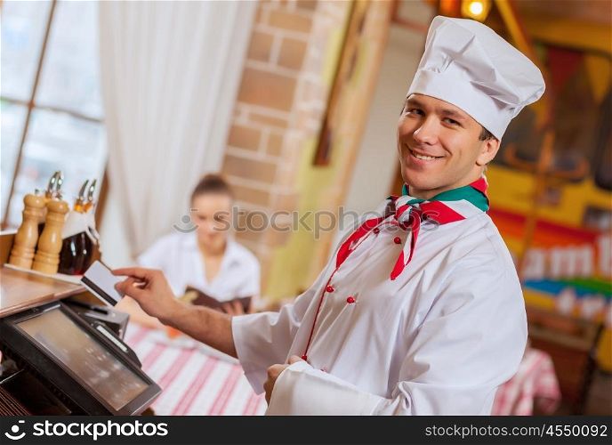 Chef at cafe. Image of handsome chef inserting card in terminal