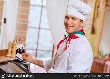 Chef at cafe. Image of handsome chef inserting card in terminal