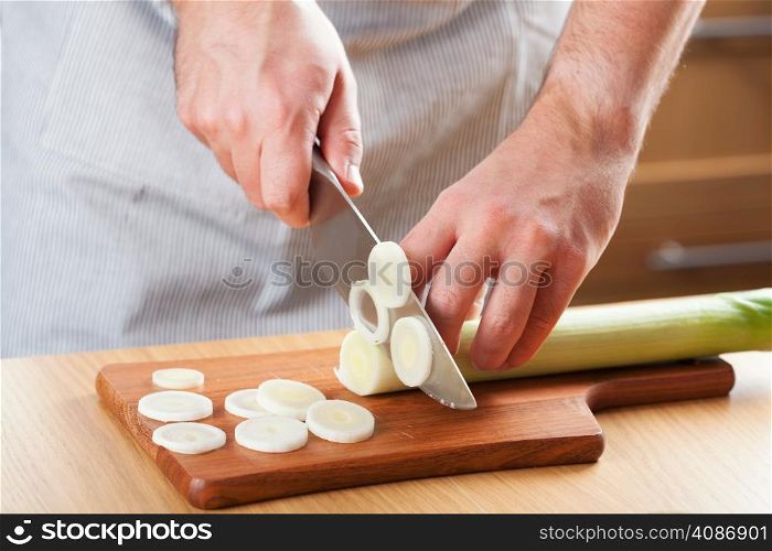 chef chopping leek in kitchen