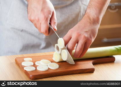 chef chopping leek in kitchen