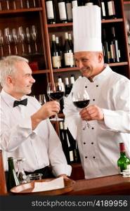 Chef cook and waiter toasting with wine smiling in restaurant