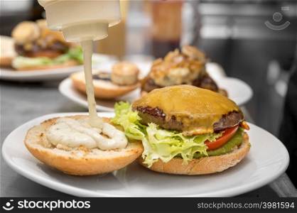 Chef cooking burger, close-up, making sandwich, fast food concept, recipe of preparing homemade hamburger with vegetables. High quality photography.. Chef cooking burger,close-up, making sandwich, fast food concept, recipe of preparing homemade hamburger with vegetables.
