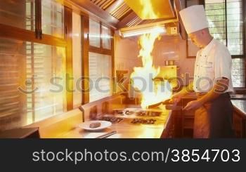Chef cooking, preparing food, professional cook in restaurant kitchen, doing flambT with pan on stove fire, steak and filet mignon. 25of26
