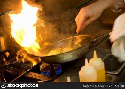 Chef cooking with a flaming pan.