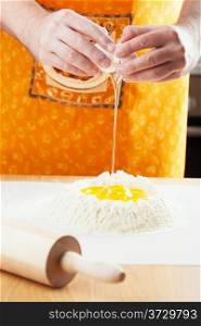 chef cracking egg into flour