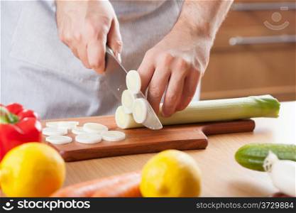 chef cutting leek in kitchen