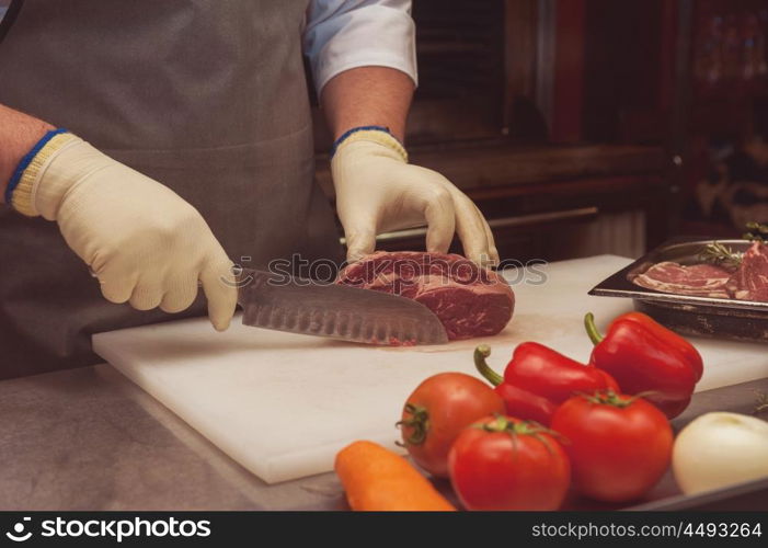 Chef cutting meat. Chef cutting meat on steaks with knife