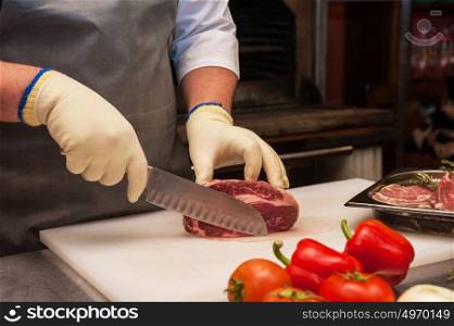 Chef cutting meat. Chef cutting meat on steaks with knife