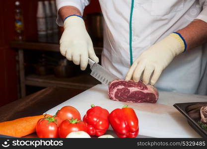 Chef cutting meat. Chef cutting meat on steaks with knife