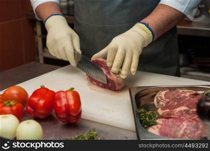 Chef cutting meat on steaks with knife. Chef cutting meat