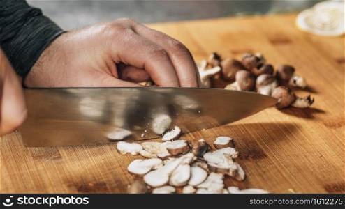 Chef Cutting Shiitake Mushrooms with Knife on a Wooden Cutting Board