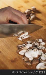 Chef Cutting Shiitake Mushrooms with Knife on a Wooden Cutting Board