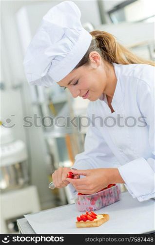 Chef cutting strawberries to decorate a tart