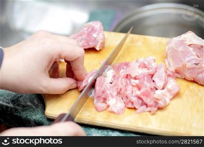Chef cutting the meat on a wooden board closeup