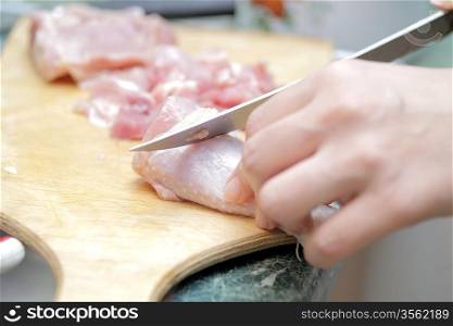 Chef cutting the meat on a wooden board closeup