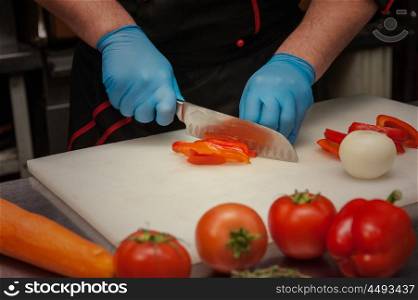 Chef cutting vegetables with knife. Chef cutting vegetables