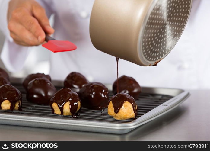 Chef decorating a chocolate profiteroles filled with cream