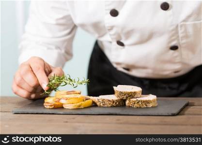 Chef decorating a pork tenderloin with potatoes