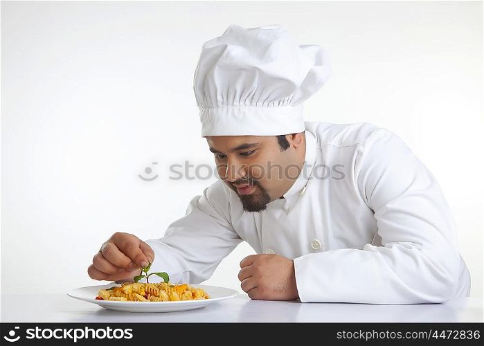 Chef decorating pasta with leaf